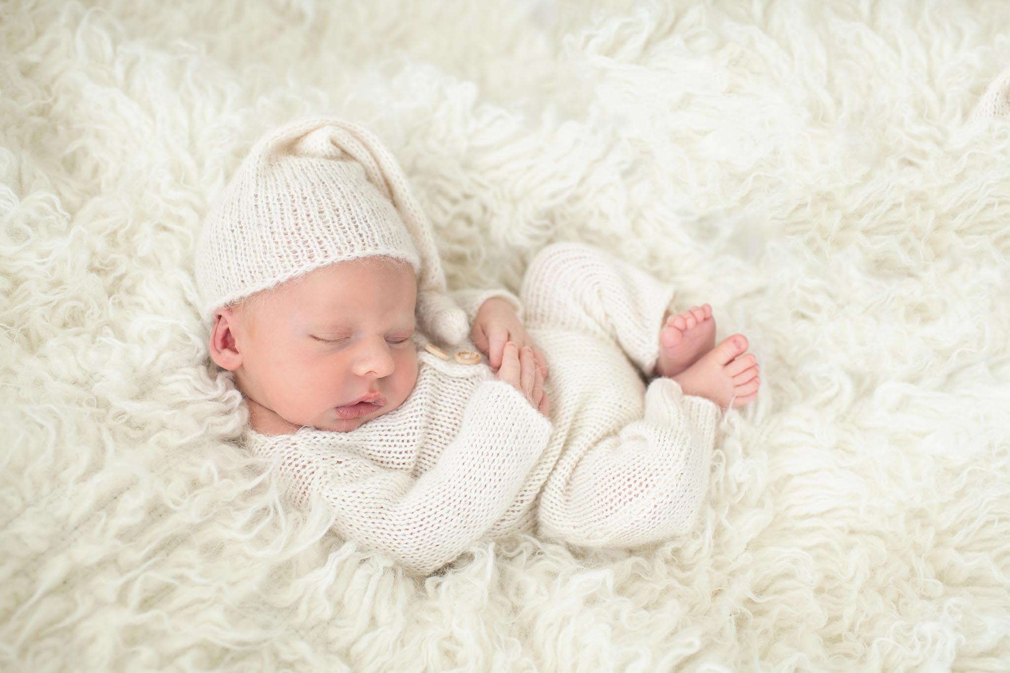 Sleeping newborn curled up with hat