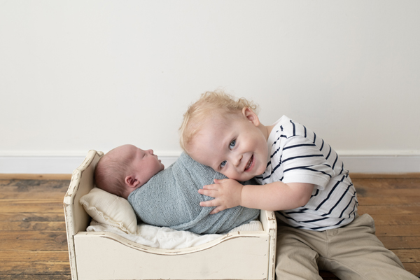 toddler-hugging-newborn-sibling-in-bed